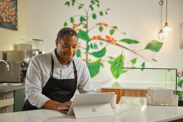 Photographie de chef debout dans une cuisine travaillant sur un appareil Surface