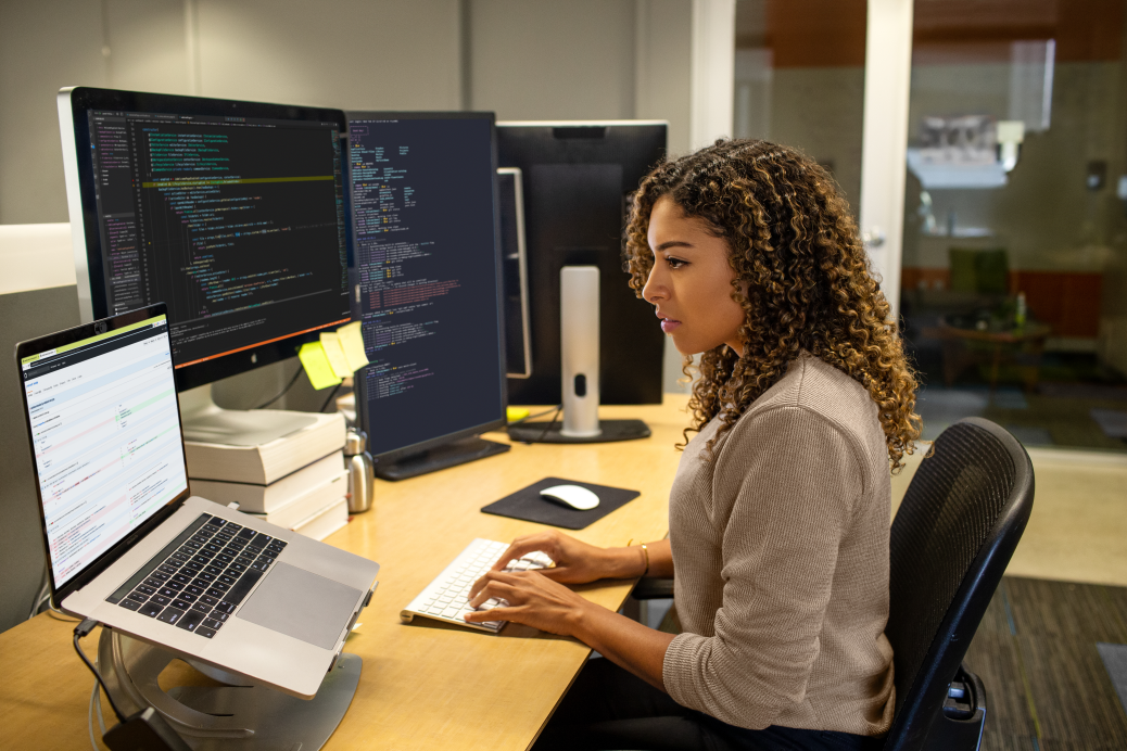De vraies personnes, de vrais bureaux. D&eacute;veloppeuse noire travaillant dans un bureau dentreprise. Travail cibl&eacute;. Elle a personnalis&eacute; son espace de travail avec une configuration multi-moniteur