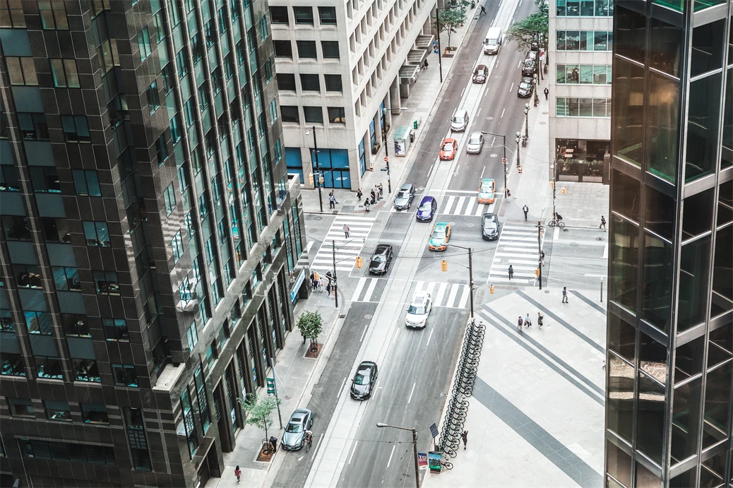 Vue de la rue du centre-ville depuis un angle &eacute;lev&eacute; &agrave; lint&eacute;rieur dun immeuble de bureaux. Les voitures traversent lintersection dans une rue &agrave; sens unique. Quelques pi&eacute;tons sont visibles sur les trottoirs et aux passages pour pi&eacute;tons