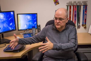 Apple gestures with his hands as he speaks at his desk. 