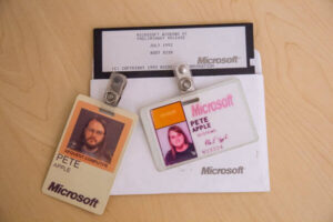 Apple’s early 90’s Microsoft vendor badges and a 1992 Windows boot disk lay on a desk.