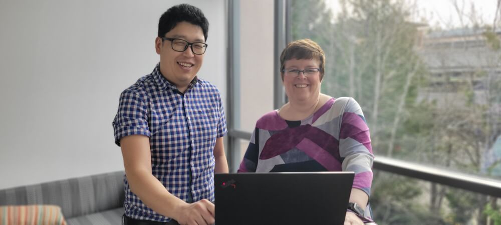 Lee and Borgmann stand together in a hallway of a Microsoft building. They are smiling at the camera.