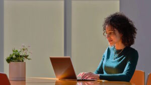 Business person uses a laptop at a conference room table.