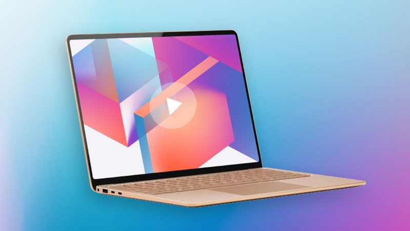 金色のノートパソコンが、青と紫のグラデーションの背景に斜めに置かれている。画面には、カラフルな幾何学模様の抽象的な画像と、白い再生ボタンがオーバーレイされている。