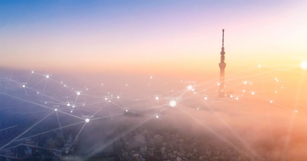 朝焼けのスカイツリーと街をカバーするクラウド ネットワークのイメージ
