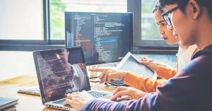 画面を見ながらプログラムを確認する男女のプログラマー