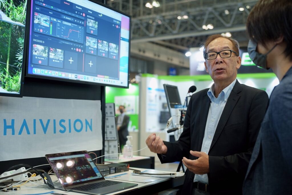 各種ディスプレイを前に自社ソリューションをお客様に説明する男性