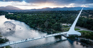 木々が立ち並ぶ広大な公園の間に流れる川とその川を渡す橋を上空から見た景色