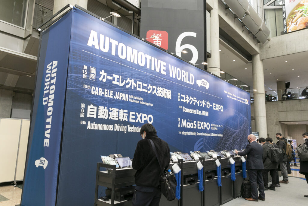 イベント看板の前に並ぶ入場受付機にて受付を行う人々