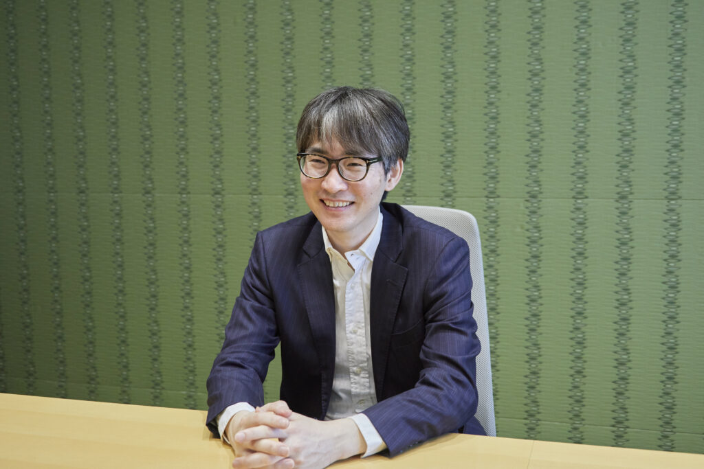 会議室の椅子に座ってインタビューを受ける男性