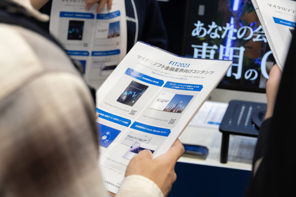 配布された「FIT2023 マイクロソフト金融業界向けコンテンツ」の冊子を読む来場者