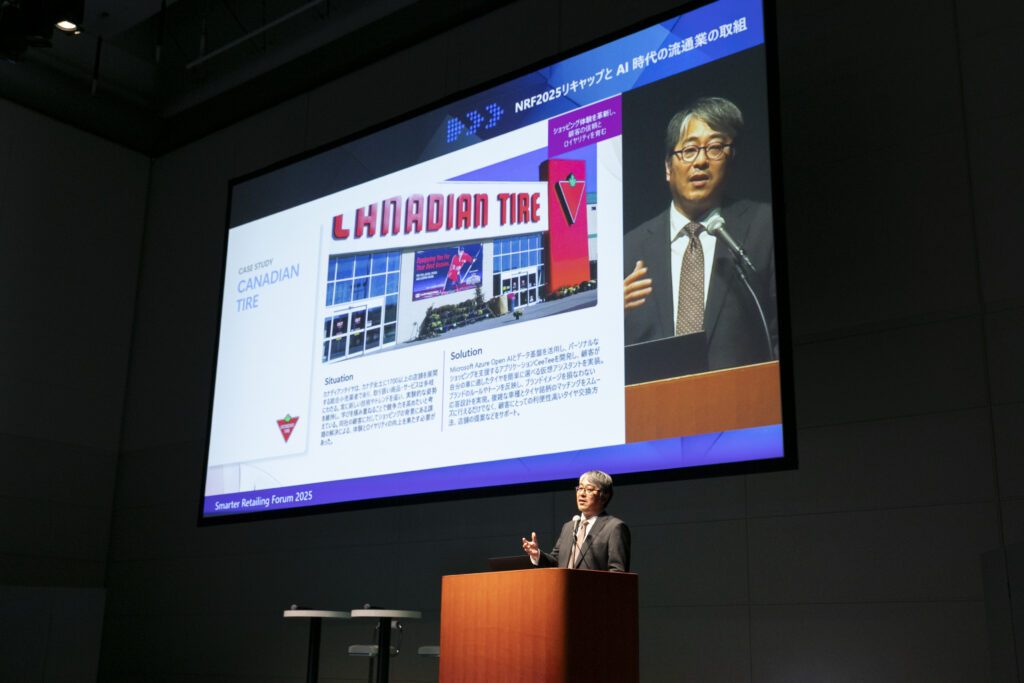 A man standing at a podium with a large screen on the wall