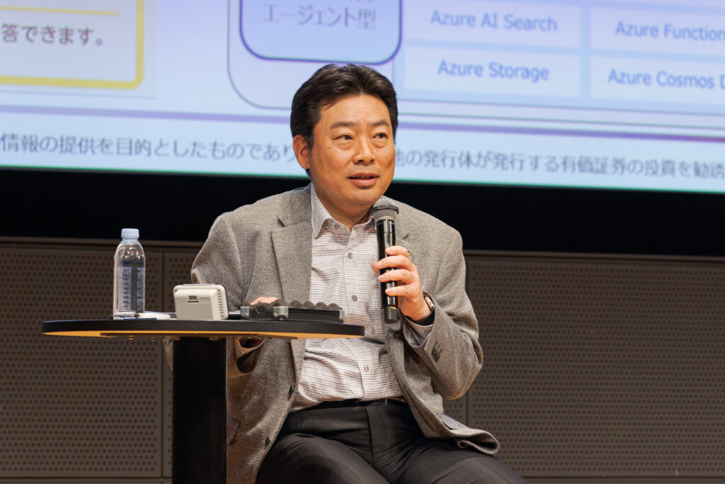 A man sitting on a stage holding a microphone