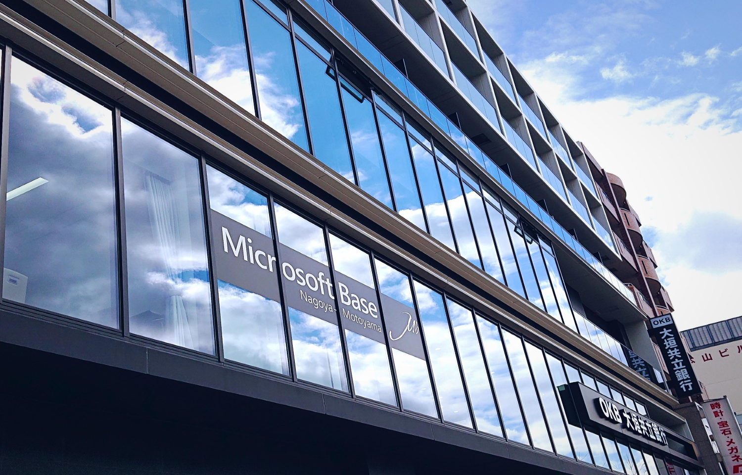 窓ガラスに「Microsoft Base Nagoya-Motoyama」と表示されたガラス張りのモダンなオフィス外観。
