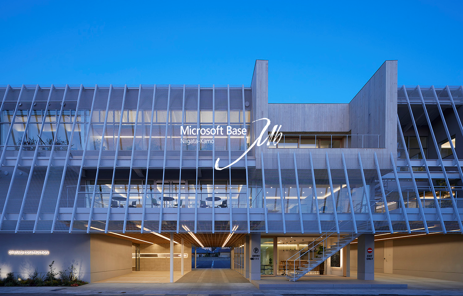 夕暮れ時に撮影された、「Microsoft Base Niigata-Kamo」のサイネージが設置されたスラットファサードのモダンな建物外観。