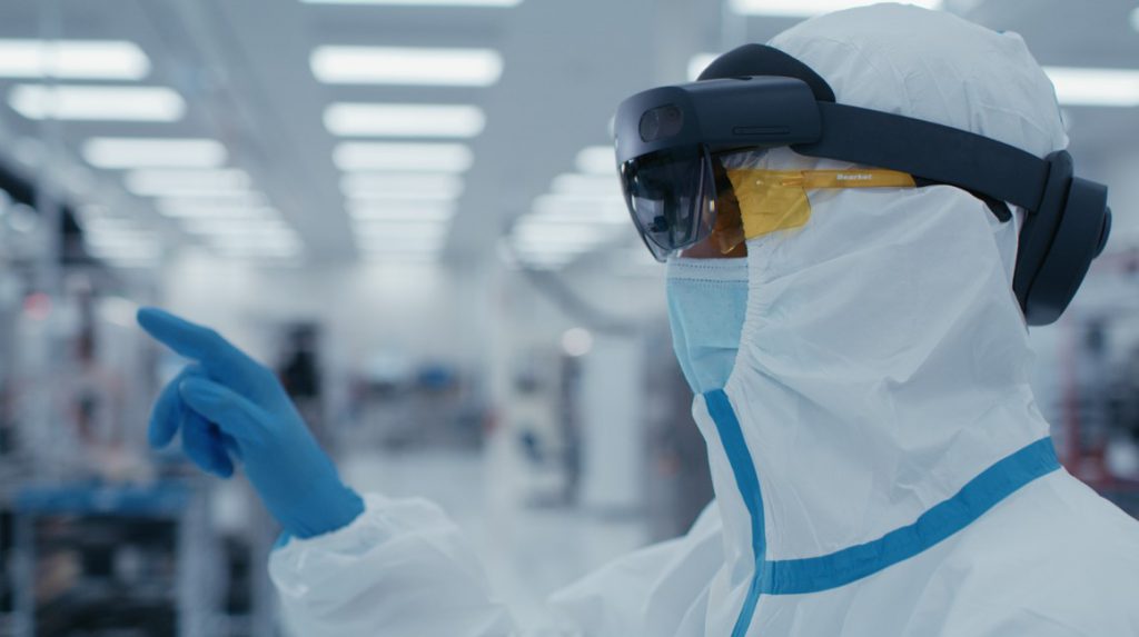 保護服を着た人が AR ヘッドセットを装着し、クリーンルーム内を指しています。
