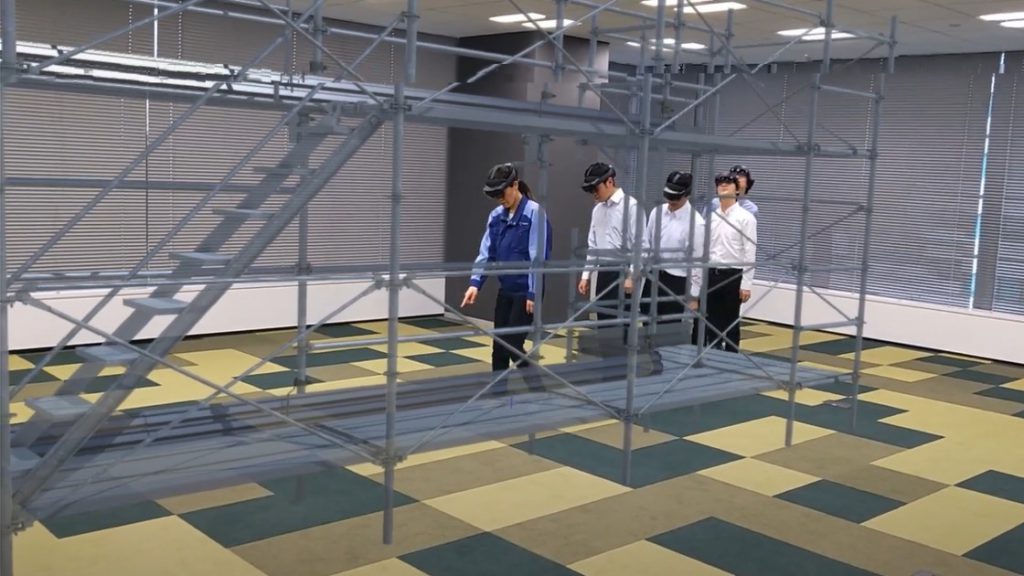 仮想マシンを装着して足場の安全構造に入る女性 1 人と男性 4 人