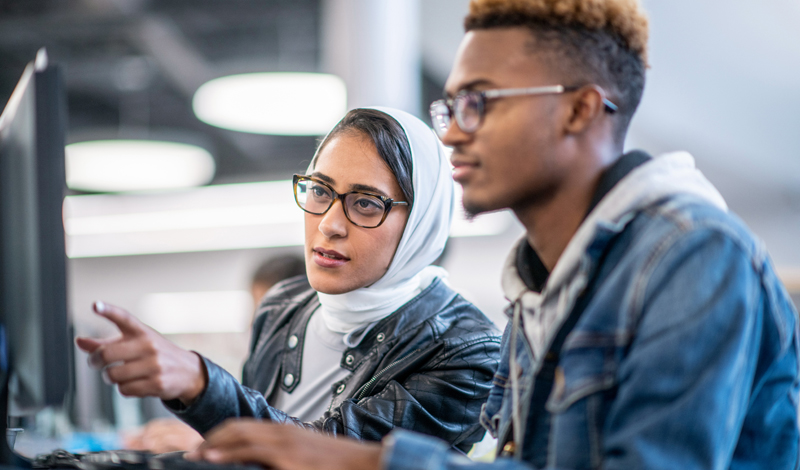 Um homem e uma mulher olhando para um monitor