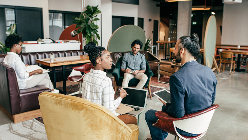 4 homens e uma mulher sentados em um escritório utilizando tablets