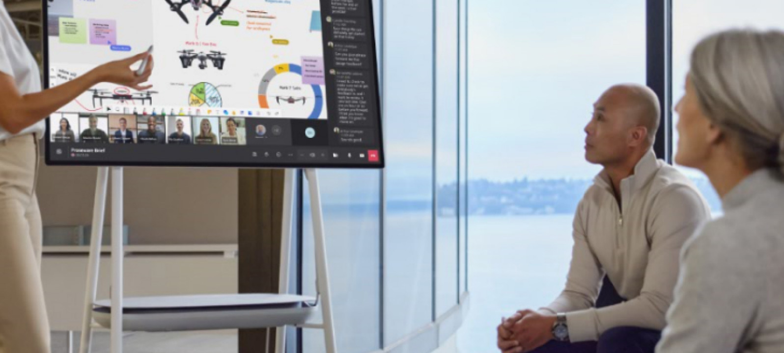 uma mulher olhando para um monitor com linhas de código e um notebook ao lado