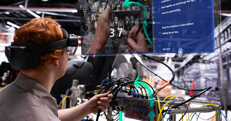 Um homem usa um dispositovo Hololens para criar uma tela virtual em uma fábrica.