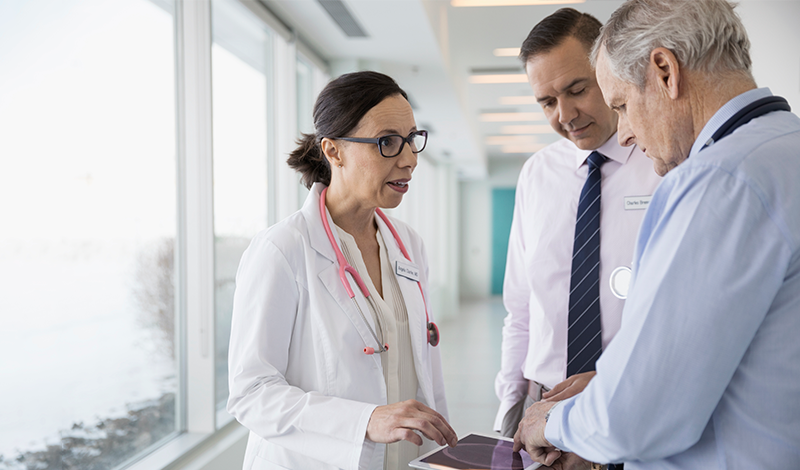 Os médicos consultam-se juntos, revendo informações num tablet digital.